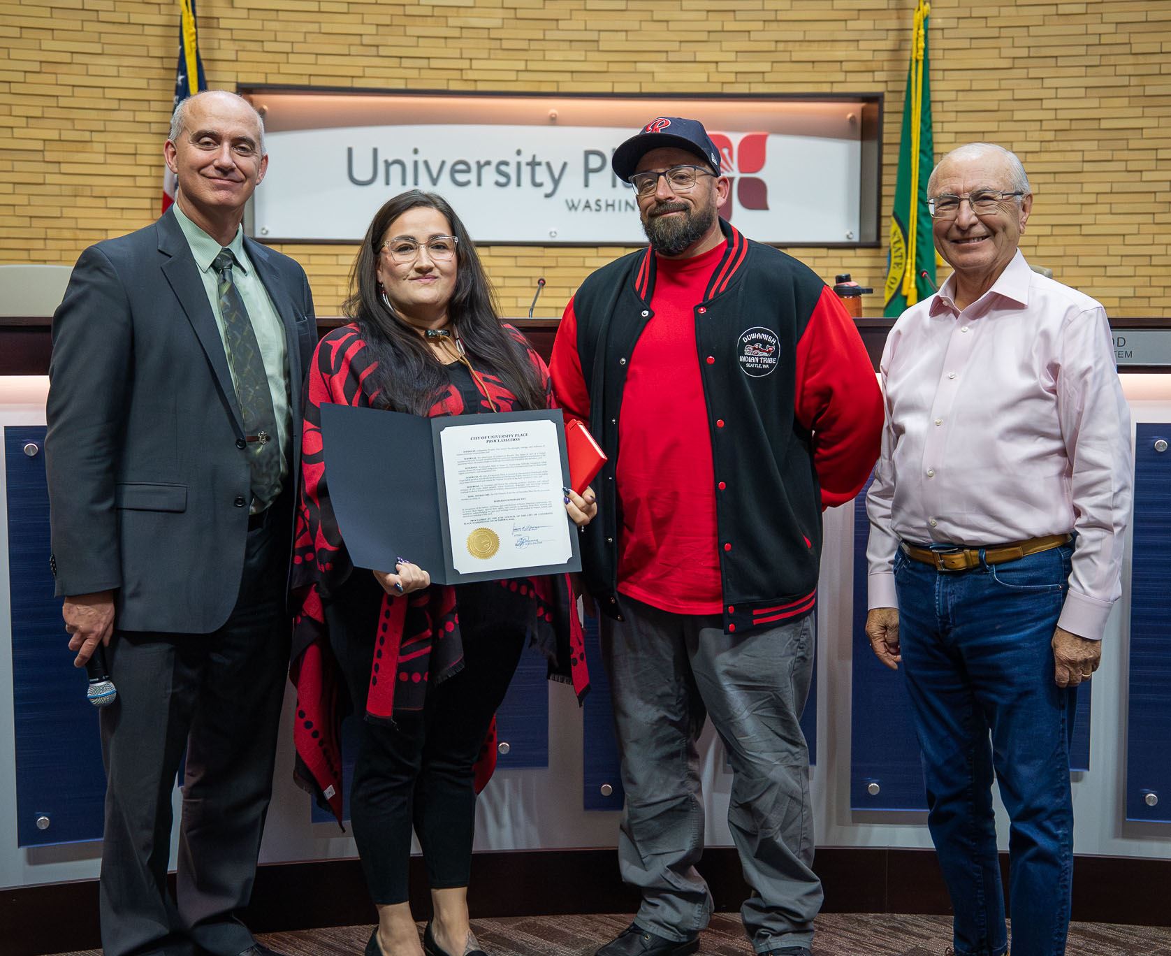 Group of men and women posing for photo with certificate in hand inside council chambers