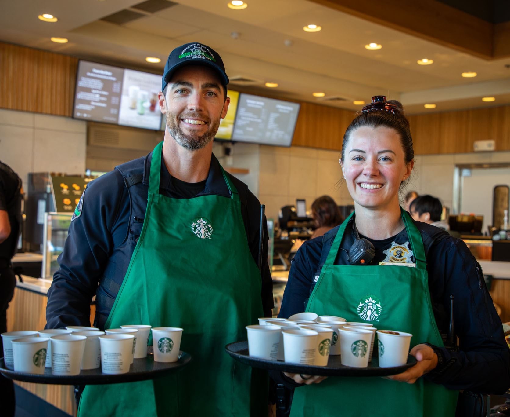Two police officers holding coffee samples wearing Starbucks aprons