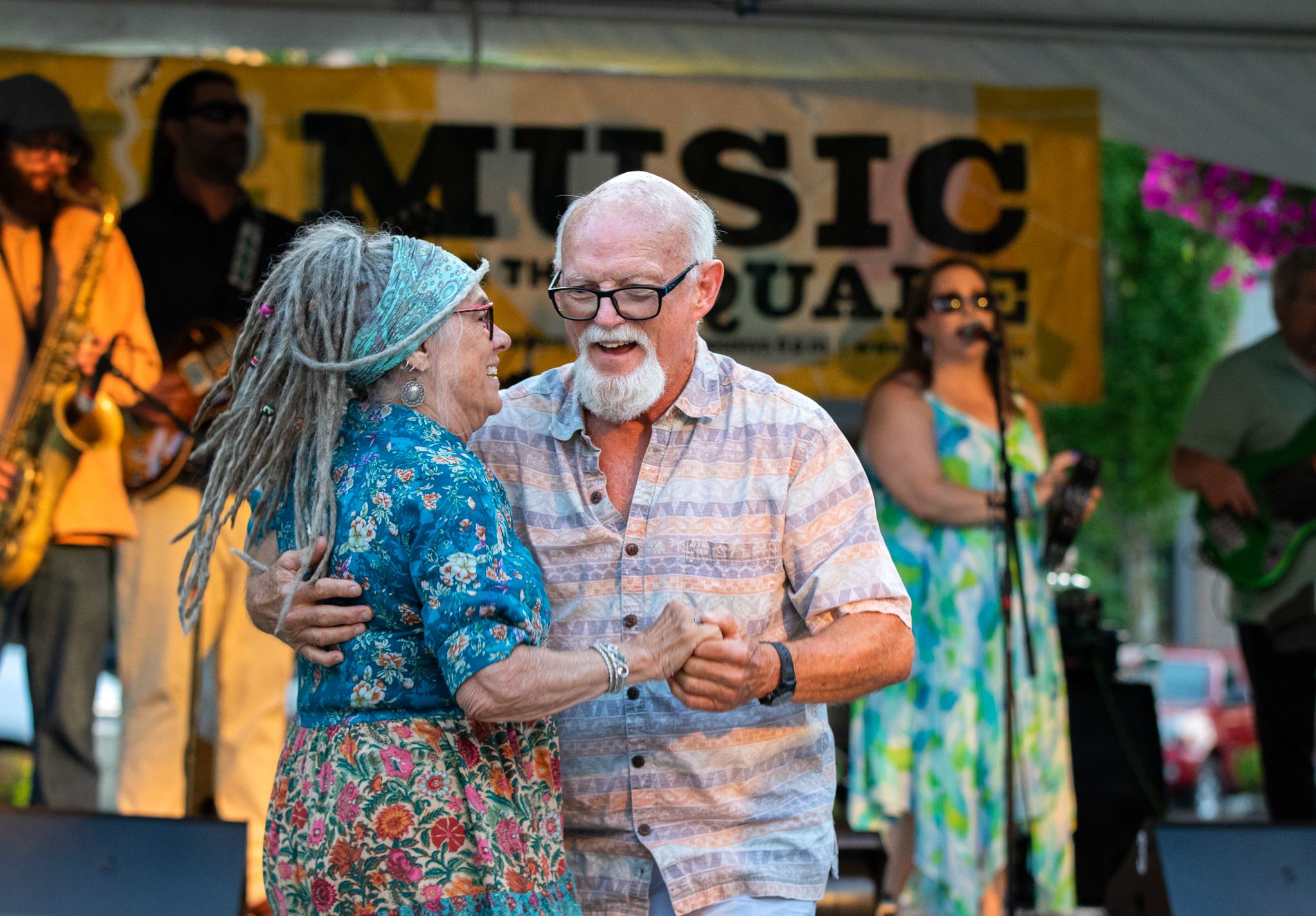 A couple dances in front of the band stage at a Music on the Square event